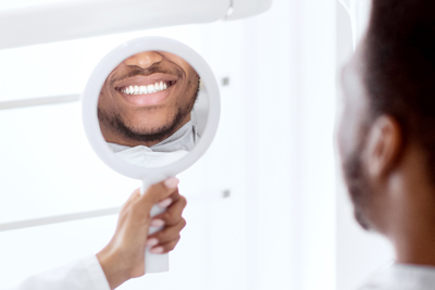 smiling man looking in mirror showcasing bright teeth dental health smile reflection